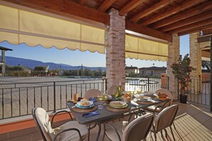 An outdoor dining area with a table set for four, overlooking a scenic landscape. - Le Terrazze PT 31 by Wonderful Italy (Toscolano Maderno)