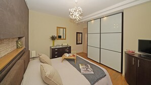 A modern bedroom with a bed, dresser, TV, and a sliding closet door. - Le Terrazze PT 31 by Wonderful Italy (Toscolano Maderno)