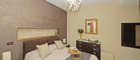 A modern bedroom with a large bed, bedside tables, a dresser, and a mirror.