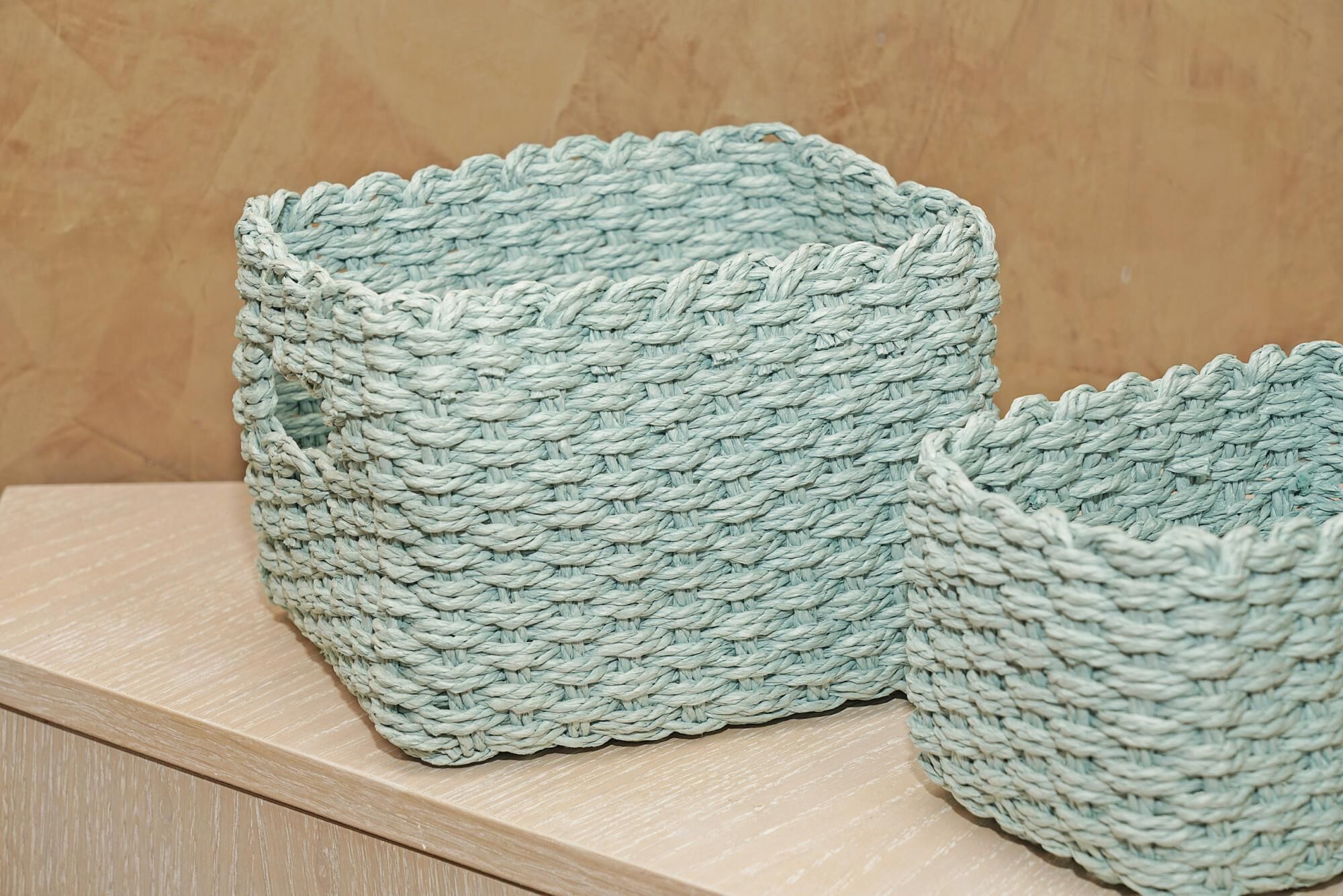 Two woven baskets on a wooden shelf.