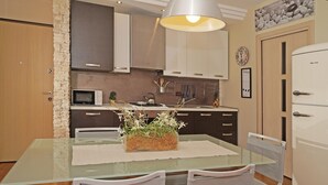 A modern kitchen with a glass dining table, white chairs, and a hanging light fixture. - Le Terrazze PT 31 by Wonderful Italy (Toscolano Maderno)