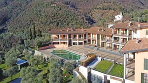 A multi-story building with a courtyard, surrounded by trees and hills. - Le Terrazze PT 31 by Wonderful Italy (Toscolano Maderno)