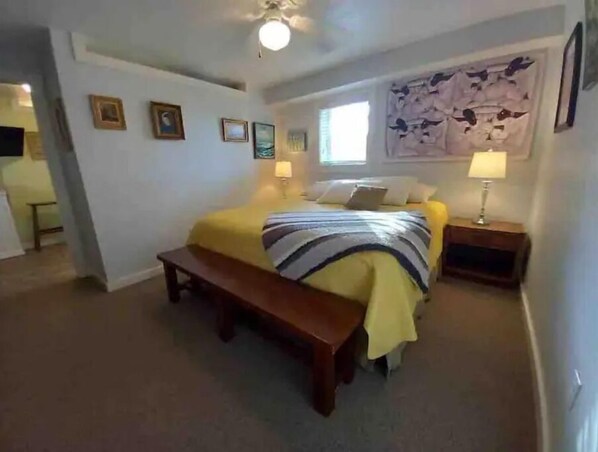 A bedroom with a bed, bedside tables, a bench, and a ceiling fan.