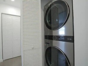 A laundry room with two wall-mounted washing machines and a white door.
