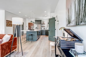 A modern living space with a kitchen, dining area, and a piano.