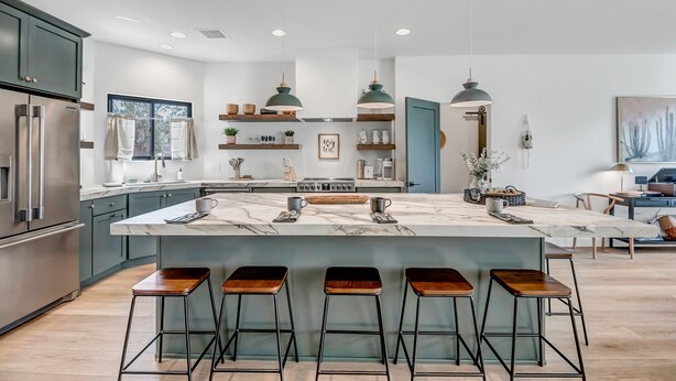 Una cocina moderna con una isla grande, taburetes de bar e iluminación colgante.