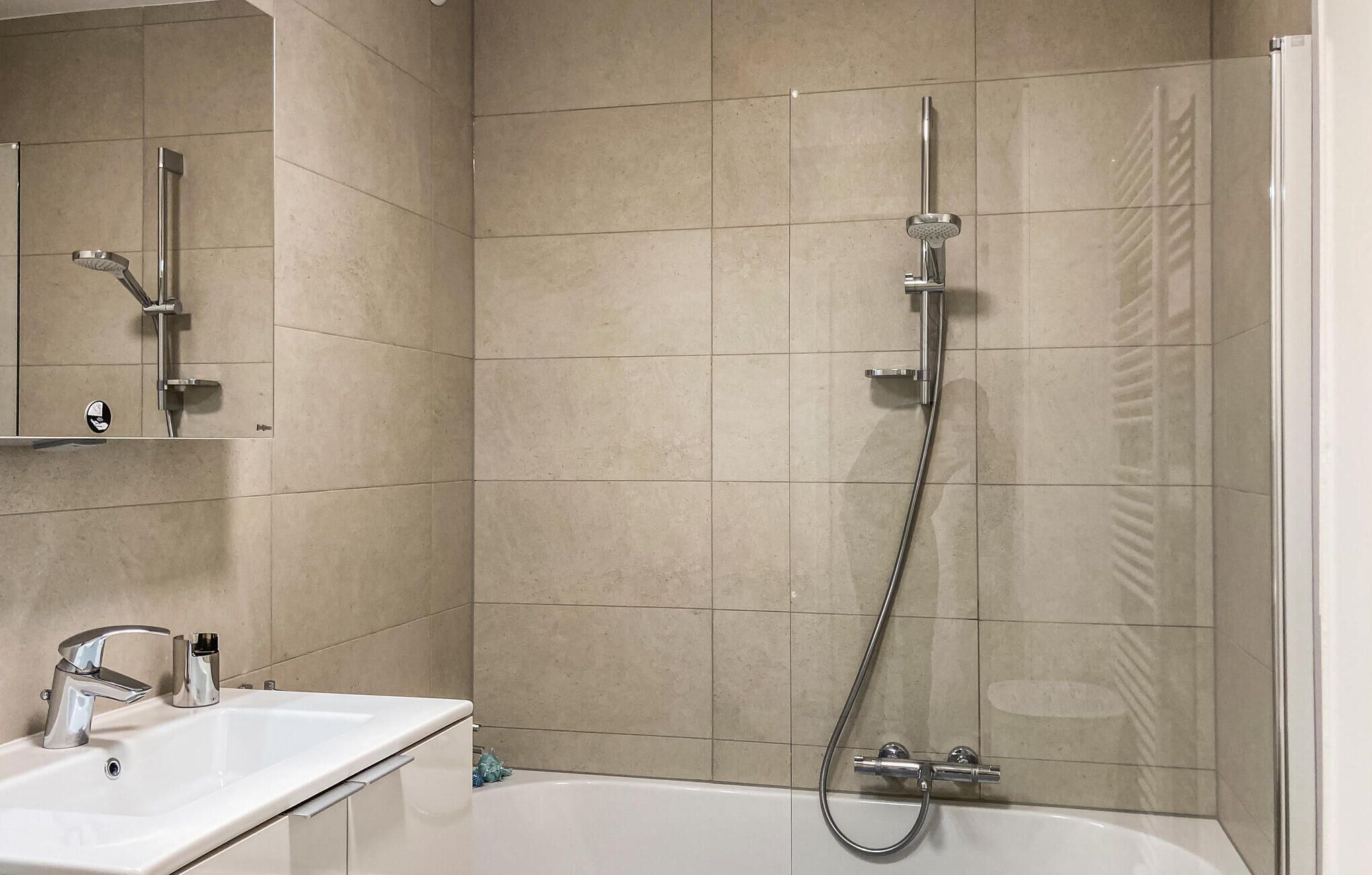 A bathroom with a bathtub, a shower with a handheld showerhead, and a sink with a modern faucet.