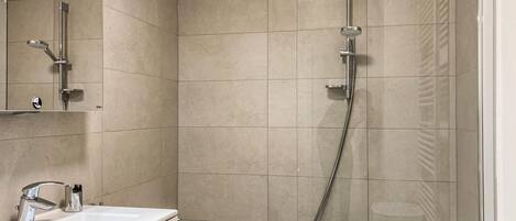 A bathroom with a bathtub, a shower with a handheld showerhead, and a sink with a modern faucet.