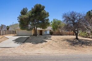 A residential house with a driveway, a front yard, and a tree. - Cosmic Rabbit - Family Fun With Hot Tub!! 3 Bedroom Home by RedAwning (Joshua Tree)