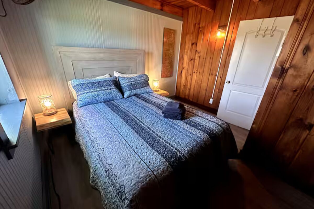 Une chambre confortable avec une couvre-lit à motifs, une tête de lit en bois et une table de chevet avec une lampe.