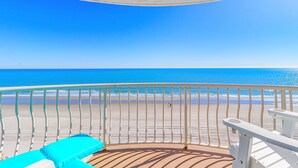 A balcony with a view of the beach and ocean.