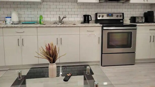 A modern kitchen with white cabinets, a stainless steel oven, a microwave, and a coffee maker. - Grande Royale (Saskatoon)