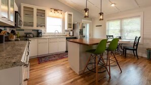 A modern kitchen with white cabinets, a wooden island, and pendant lighting.