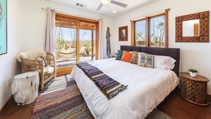 A spacious bedroom with a large bed, a ceiling fan, and a view through a sliding glass door. - Constellation Compound - Your Own Private 10 Acres 4 Bedroom Home by RedAwning (Joshua Tree)
