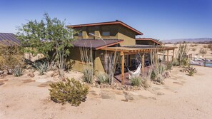 A desert-style house with a patio, surrounded by cacti and desert plants. - Constellation Compound - Your Own Private 10 Acres 4 Bedroom Home by RedAwning (Joshua Tree)