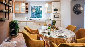 Uma cozinha moderna com armários brancos, uma janela grande e um espaço de refeições com uma mesa redonda e cadeiras amarelas.