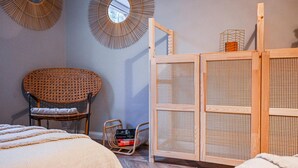 Um quarto com uma cadeira de vime, um armário de madeira com frente trançada e um espelho na parede.