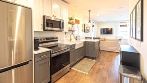 Una cocina moderna con electrodomésticos de acero inoxidable, armarios blancos y piso de madera.