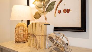 A bookshelf with books, a lamp, and a framed botanical illustration.