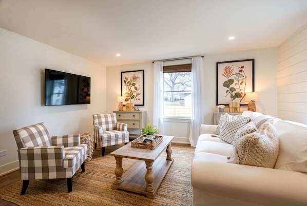 A living room with a sofa, armchairs, a coffee table, and artwork on the walls.