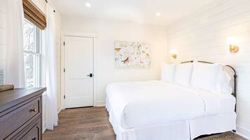 Une chambre à coucher comprenant un lit, une commode, une porte et un luminaire fixé au mur.