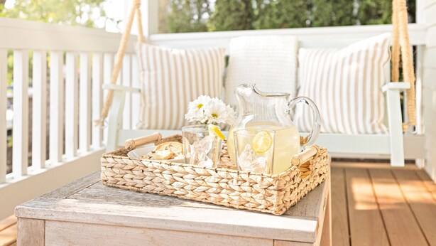 A wicker tray with a pitcher and glasses on a wooden table on a porch. - Kildahl House - Boutique Farmhouse Suite #3 (West Dundee)
