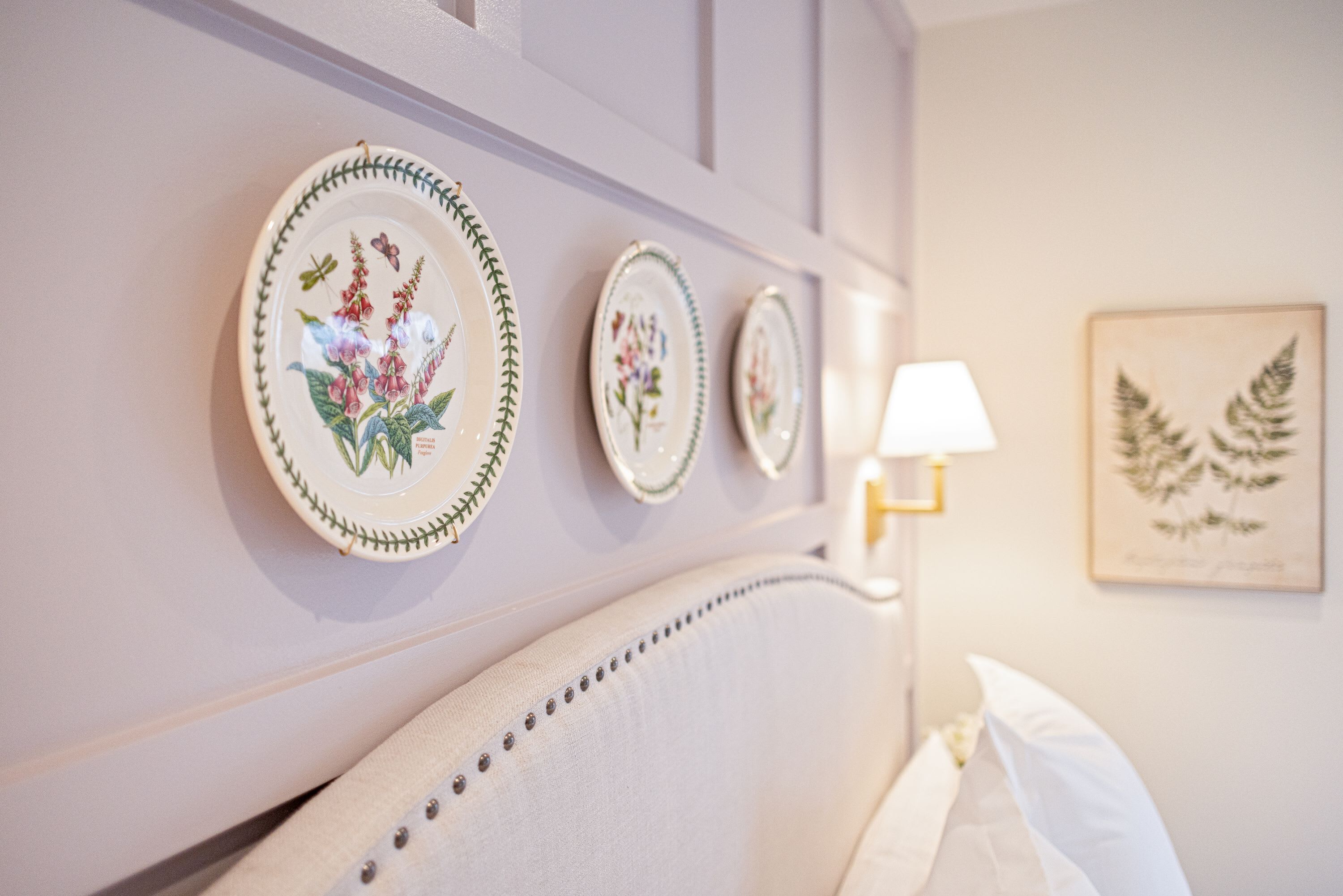 Un mur orné de trois assiettes décoratives et d’une estampe botanique encadrée.
