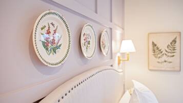 Un mur orné de trois assiettes décoratives et d’une estampe botanique encadrée.