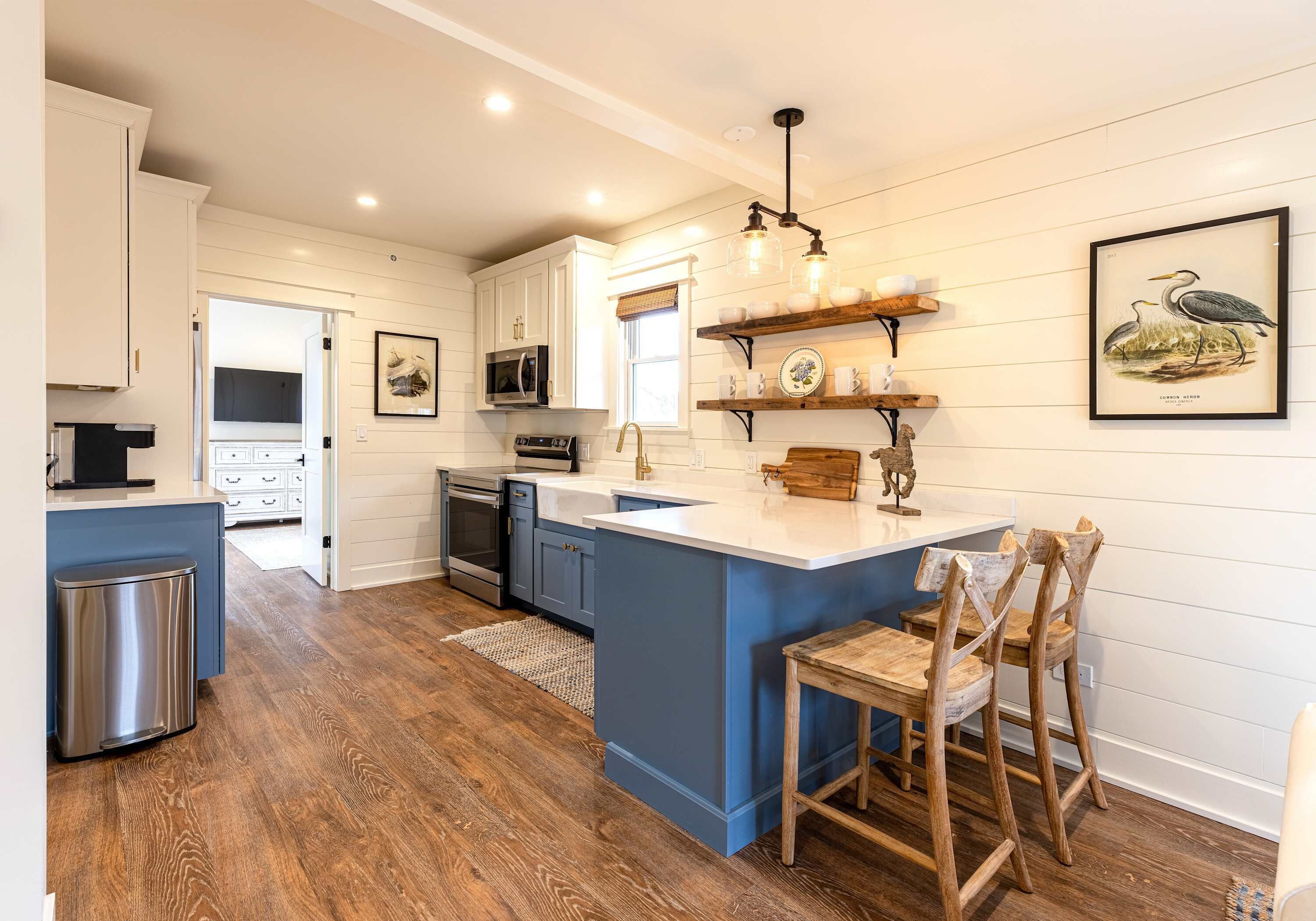 A kitchen with a blue island, white cabinetry, and a wooden chair.