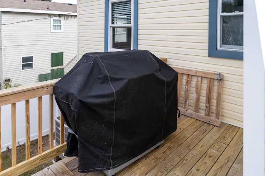A covered grill on a wooden deck.