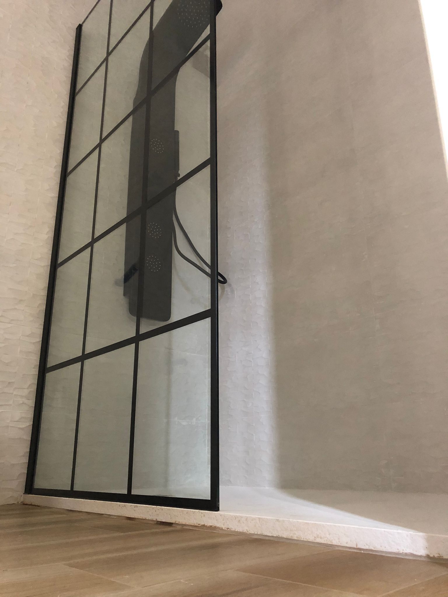 Una stanza con un'ampia finestra a cornice nera e vetri decorati.
