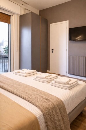 Un dormitorio con cama, armario, televisor y radiador.