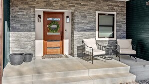 A modern house entrance with a stone facade, a wooden door, and a welcome mat.