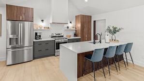 A modern kitchen with a central island, stainless steel appliances, and wooden cabinetry.