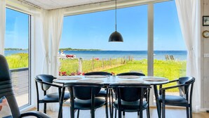 A dining area with a table set for six, large windows, and a hanging pendant light. - Amazing home in Sjølund with WiFi (Sjølund)