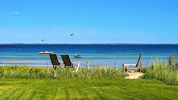 A beach with two lounge chairs, a wooden deck, and a view of the sea. - Amazing home in Sjølund with WiFi (Sjølund)