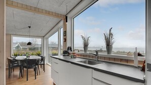 A modern kitchen with a large window, wooden ceiling, and a dining area with a table and chairs. - Amazing home in Sjølund with WiFi (Sjølund)