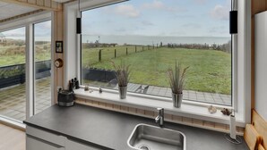 A kitchen with a large window overlooking a grassy field and a body of water. - Amazing home in Sjølund with WiFi (Sjølund)