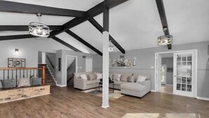 Ein geräumiges Wohnzimmer mit Holzboden, einer Treppe und zwei Sofas.