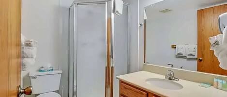 Une salle de bain avec une douche à parois de verre, des toilettes, un lavabo avec un miroir et des meubles en bois.