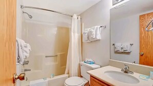 Ein Badezimmer mit Dusche, Toilette, Waschbecken und Spiegel.