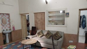 Una sala de estar con un sofá, una mesa redonda de centro, un aparador de madera y un estante de pared.