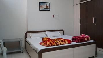 A bedroom with a bed, a nightstand, a wardrobe, and a picture on the wall.