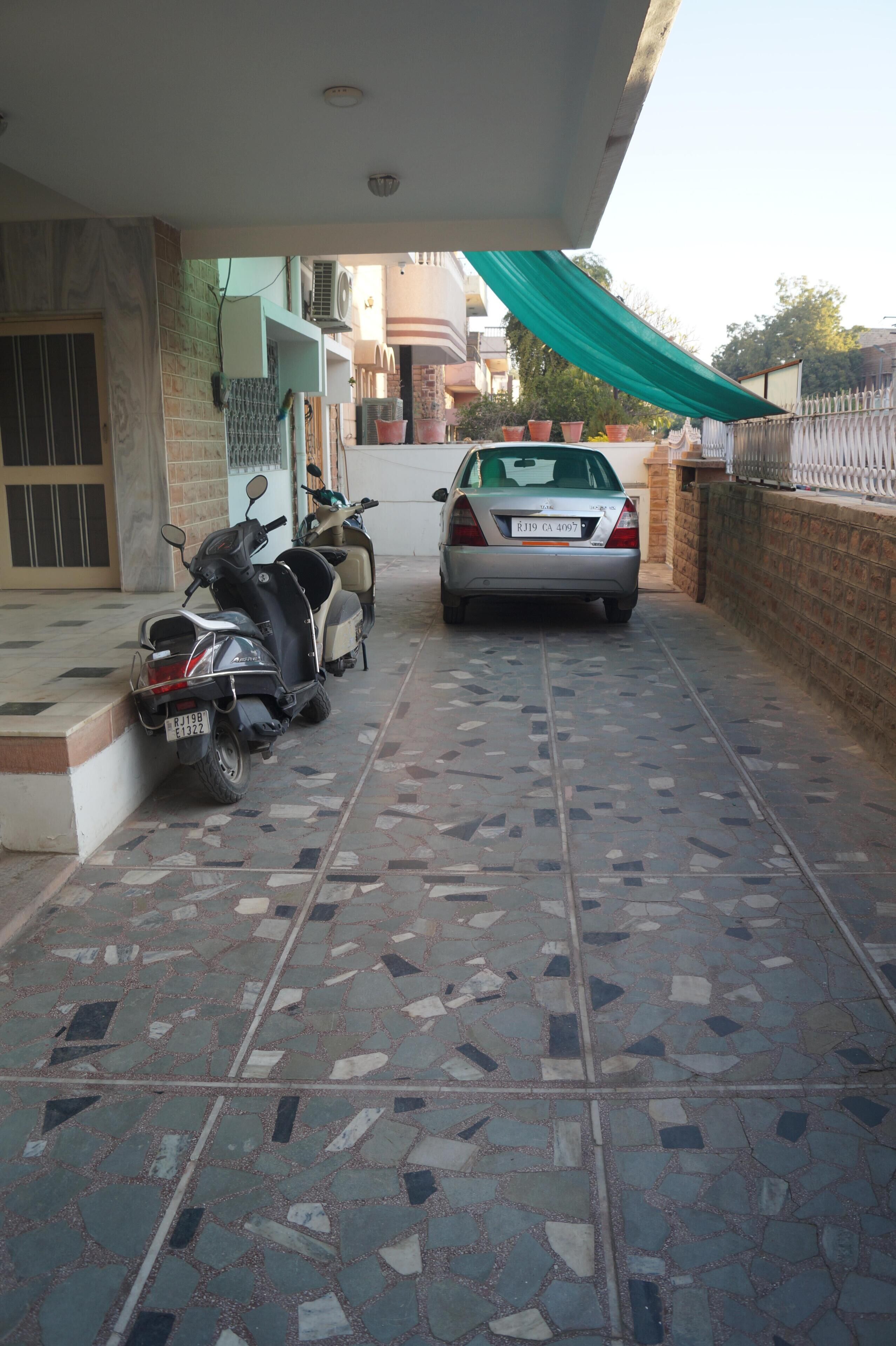 Eine geflieste Terrasse mit einem Auto und zwei Rollern.