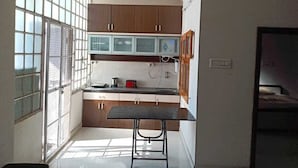 Una cocina compacta con armarios de madera, una mesa pequeña y una ventana con persianas.