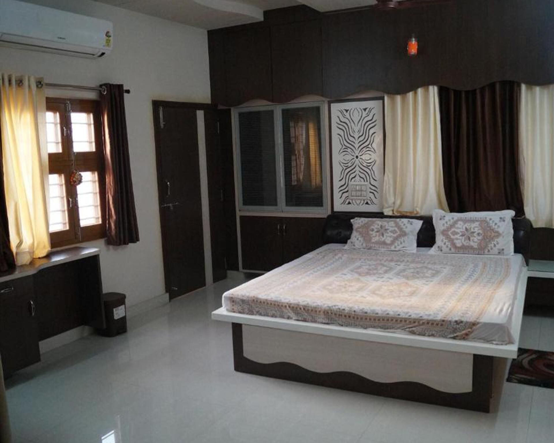 A bedroom with a large bed, dark wooden wardrobe, and a window with curtains.