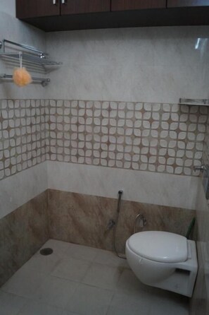 Une petite salle de bain avec des toilettes, une douche et un mur carrelé.