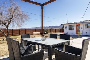 Eine Außenpatio mit Tisch und Stühlen, einem Holzzaun und einem Gebäude im Hintergrund.