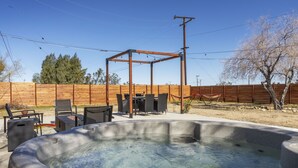 Un bain à remous agrémenté d’une pergola en bois et de mobilier d’extérieur, situé dans un jardin.