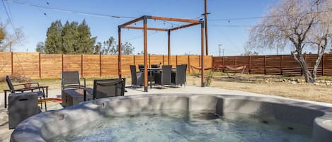 Una vasca idromassaggio con una pergola in legno e mobili da giardino in un cortile.
